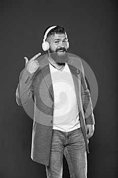 Look at my headset. Hipster point finger at headset grey background. Bearded man listen to music playing in stereo