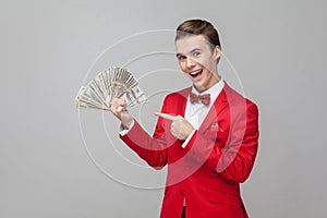 Look at my money. Portrait of extremely happy man pointing at bunch of dollars, expressing joy