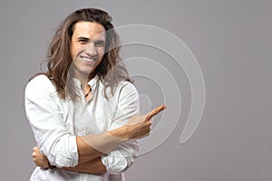 Look over there. Handsome cheerful man with long hair shows ad