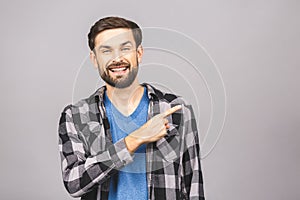 Look over there! Happy young handsome man in casual pointing away and smiling while standing