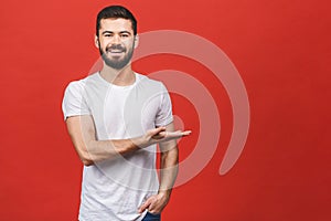Look over there! Happy young handsome man in casual pointing away and smiling while standing against red background