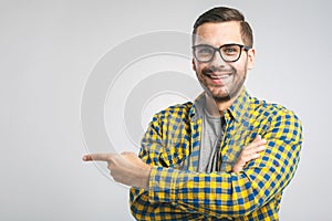 Look over there! Happy young handsome man in jeans shirt pointing away and smiling