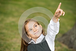 Look over there. Little child point finger up outdoors. Little girl wear school uniform. Back to school. Kids education