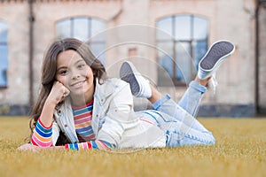 A look of perfection. Happy girl rest on grass outdoors. Beauty look of little child. Vogue look. Casual fashion look