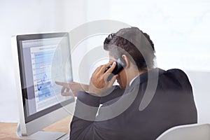 Look at those share prices. Shot of a businessman talking on the phone and pointing at a graph on his computer screen.