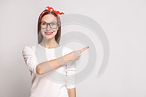 look at this side. pointing finger. portrait of beautiful emotional young woman in white t-shirt with freckles, glasses, red lips