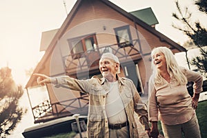 Joyful laughing mature pair standing near house