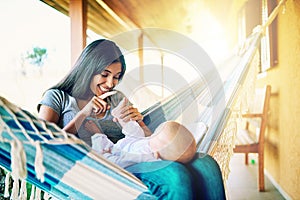 Look at these tiny little toes. a cheerful young mother relaxing on a hammock with her infant son outside at home during