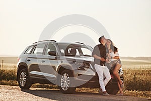 Look up. Lovely couple near their new modern car at weekend time