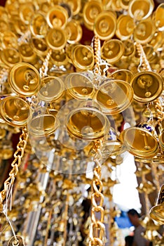 Look up view of of many small golden bells was hung in a group in Thai temple.