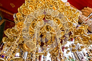 Look up view of of many small golden bells was hung in a group in Thai temple.