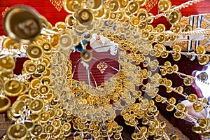 Look up view of of many small golden bells was hung in a group in Thai temple.