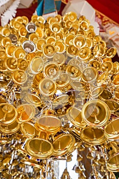 Look up view of of many small golden bells was hung in a group in Thai temple.