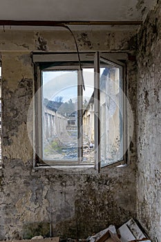 A look through a window of an old looted factory falling apart crumbling bricks gravel concrete