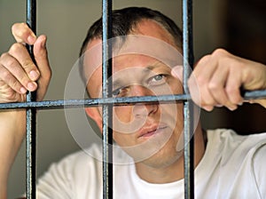 The look of a young man from behind metal bars