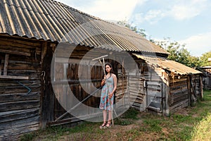 LookBook portrait of a girl in a rustic vintage dress with rakes near a rural barn and cowshed in a courtyard