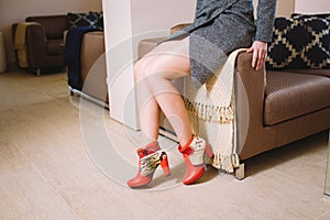 Lookbook woman`s legs in red leather boots in the interior