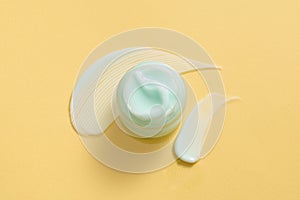 Looking from above, a jar of dense-textured moisturizer in a light blue against a yellow background