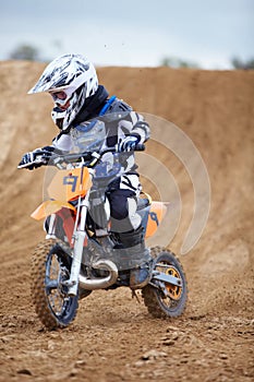 Looking ahead to the next bend. A young motocross rider coming down a hill on a dirt track.