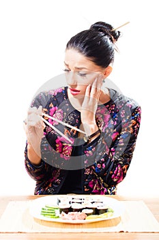 Looking anxiously at Japanese sticks attractive beautiful brunette woman sushi on the plate on white background isolated