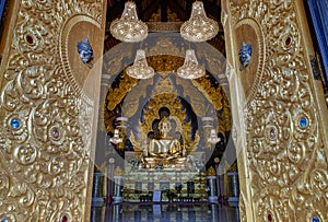 Looking through the beautiful architecture temple door of The golden buddha image within Wat Phra That Doi Phra Chan in Lampang