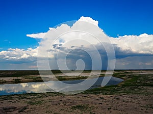 Looking at beautiful raining cloud from afar with blue sky background and water reflection during game drive