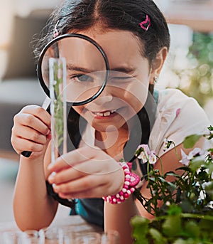 Looking at the bigger picture. Cropped shot of an adorable little girl looking through a magnifying glass while