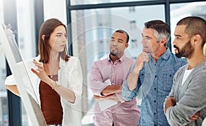 Looking at the bigger picture. four businesspeople working at a whiteboard.