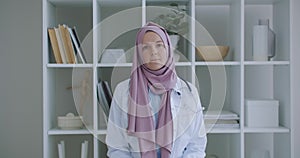 Looking at the camera listening woman doctor in hijab looks at the camera and listens to the patient. A video conference