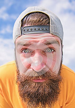 Looking so closely. Serious hipster in street fashion wear on cloudy sky. Brutal man with long beard and mustache