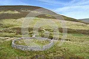 Looking down on circular sheepfold with small footbridge behind