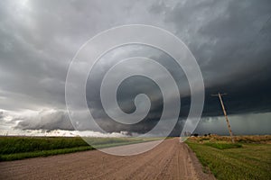 Looking down a dirt road at a supercell thunderstorm.
