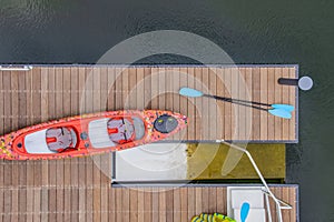 Looking down on a dock in the water with a kayack and paddles and life vests beside a kayac lanching platform