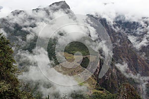 Looking down at Machu Picchu and the Vilcabamba Mountain Range through the clouds from atop Huayna Picchu
