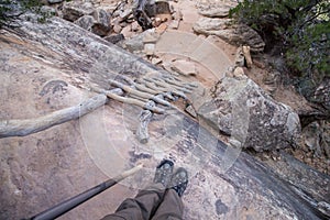 Looking down an old wooden ladder leaning against a rocky cliff, first person perspective.