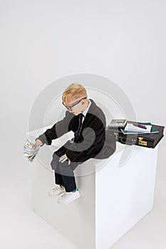 Portrait of little boy, child businessman in huge father& x27;s suit with big retro attache case isolated on white studio