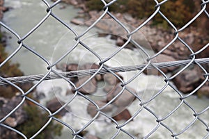 Looking down at a river through a chainlink fence