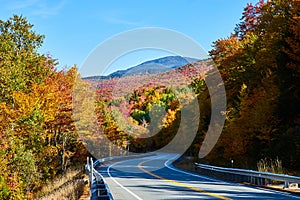 Looking down road from side in mountains during peak fall with colorful foliage