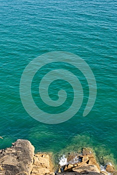 Looking down to rocks and blue pristine sea Ocean background with copy space