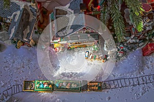 Looking down at under-the-tree Christmas village with train with presents on top and Santas Workshop and a gas station and