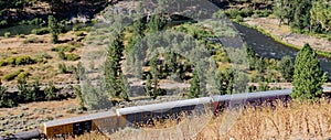 Looking down into a valley with a fright train near a river