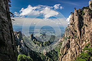 Looking down a valley with impossibly steep cliffs to a city very far in the distance in Huang Shan China