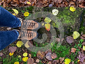 Looking down at woman`s feet in hiking boots on a rainy colorful