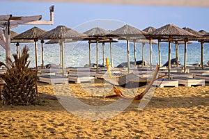 Looking at empty deck chairs and parasols at the beach bar by the sea. It is a beautiful sunny day by the sea. Copy space