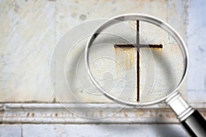 Looking for faith - concept image with a magnifying glass in front of a Christian cross