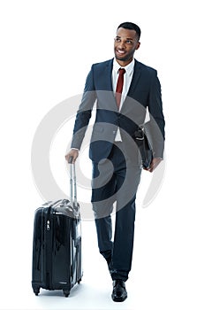 Looking forward to the day. A handsome young african american businessman walking alongside his suitcase while isolated