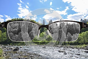 Looking through glasses to black and white river and forest landscape focused in women`s glasses. Color blindness. World