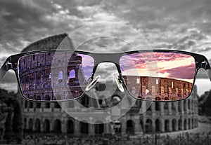 Looking through glasses to colorful Colosseum Coliseum in Rome at sunset against purple cloudy sky, Italy. Different world