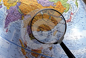 Looking at globe using magnifying glass (Asia Region) photo