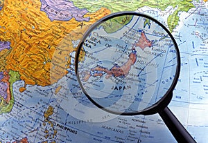 Looking at globe using magnifying glass (Asia Region)